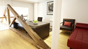 Een moderne woonkamer met een houten trap, een eethoek met een tafel en stoelen, en een rode bank.