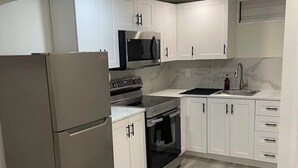 Een moderne keuken met witte kasten, roestvrijstalen apparatuur en een grijze vloer.