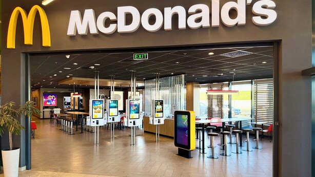 Un restaurant McDonald's doté d’un intérieur moderne, de bornes de commande numériques et d’un sol carrelé propre.