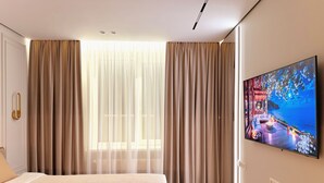 Une chambre d’hôtel avec un lit, des rideaux, une télévision et une fenêtre.