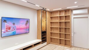 Un salon moderne doté d’un téléviseur à écran plat, d’étagères intégrées et d’une porte blanche.