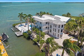 A waterfront property with a large house, a dock, and a boat. - Aurum Gem Oceanview with Pool & Private Marina (Key Largo)
