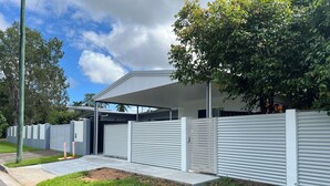 Un bâtiment moderne doté d’un garage fermé, d’une entrée sécurisée par un portail et d’une pelouse bien entretenue.