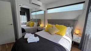 Une chambre d’hôtel équipée d’un lit, d’un miroir, d’une table de chevet avec une lampe et d’un appareil de climatisation.