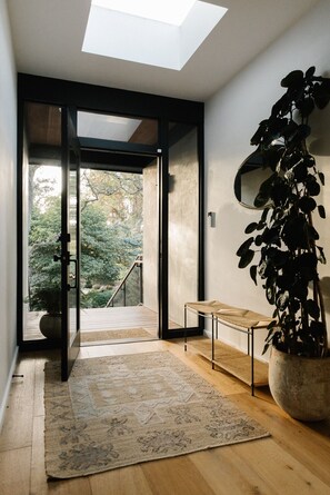 A modern interior with a skylight, a potted plant, a bench, and a view of a garden outside. - Secluded Montecito Modern Retreat (Toro Canyon)