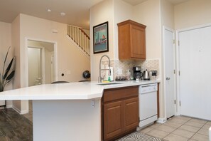 A kitchen with a white island, wooden cabinets, a coffee maker, and a framed picture on the wall.