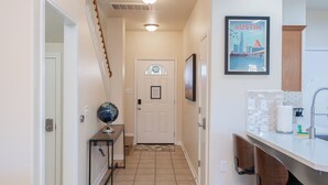 A hallway with a white door, a globe on a console table, and a framed picture of Austin, Texas. - Amazing 3 King Beds  BackYard  FireTV  Spacious (Austin)