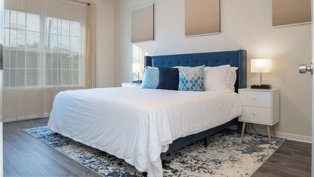 A modern bedroom with a large bed, a nightstand, and a window with sheer curtains. - Amazing 3 King Beds  BackYard  FireTV  Spacious (Austin)