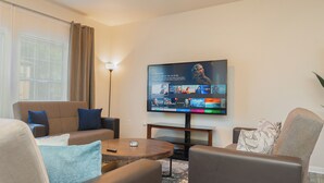 A modern living room with a flat-screen TV, comfortable seating, and a coffee table. - Amazing 3 King Beds  BackYard  FireTV  Spacious (Austin)
