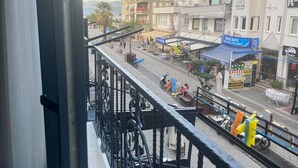 A balcony with a metal railing overlooking a street with buildings, shops, and a parked scooter. - Fethiye Marinada lüks daire (Fethiye)