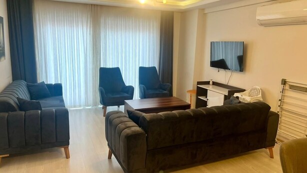 A modern living room with a sofa, armchairs, a coffee table, and a TV. - Fethiye Marinada lüks daire (Fethiye)