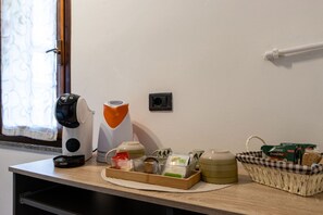 Une petite cuisine équipée d’une machine à café, d’une bouilloire, d’un panier de collations et d’un petit réfrigérateur.