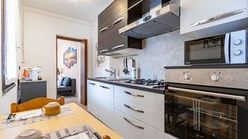 Une cuisine moderne équipée d’un four à micro-ondes, d’une cuisinière, d’un four et de meubles de rangement blancs.