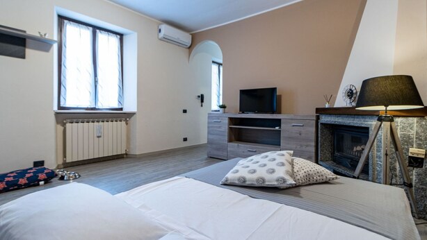 Een slaapkamer met een bed, een televisie, een open haard en een raam.