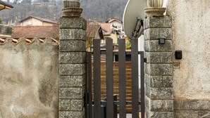 Een omheind toegangspunt met stenen pilaren en een metalen poort.