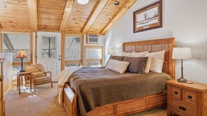 Una camera da letto con un letto in legno, comodini, una sedia e una finestra con persiane.