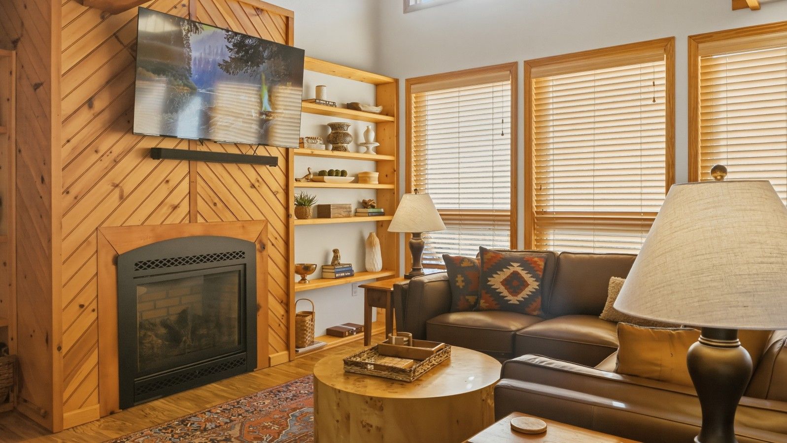 A cozy living room with a fireplace, wooden shelves, a sofa, and a lamp.