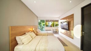 A modern bedroom with a large bed, a TV mounted on the wall, and a view of the outdoor area. - The One & Only Luxe Beachfront Villa ~ Hotel Zone (Puerto Vallarta)