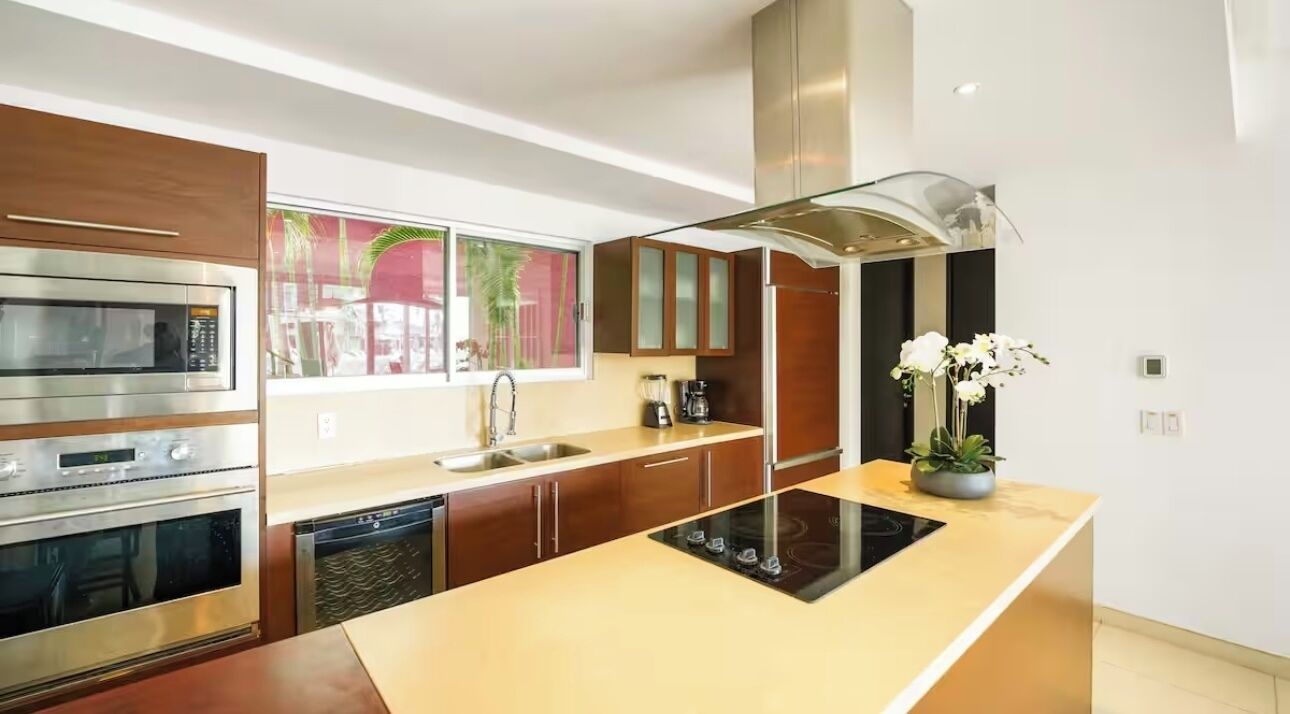 A modern kitchen with built-in appliances, a central island, and a window with a view.