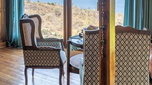 A room with wooden floors, patterned chairs, a table, and a view of the sea. - Chalet with 3 bedrooms and panoramic views (Karangasem)
