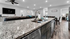 Une cuisine moderne dotée de plans de travail en granit, d’appareils électroménagers en acier inoxydable et d’un ventilateur de plafond.