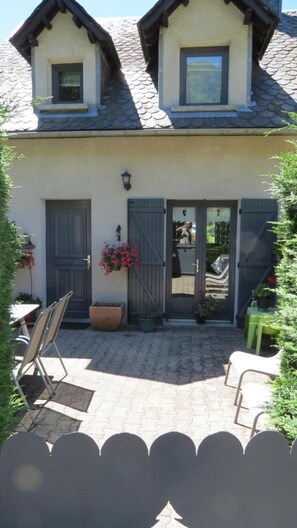 A two-story house with a tiled patio, a front door, and a small window on the upper floor. - LE MOULIN - BESSE AND SAINT ANASTAISE (BESSE ET SAINT ANASTAISE)