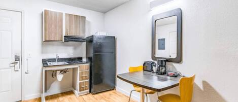 A compact kitchen with a refrigerator, a sink, and a small dining table with chairs.