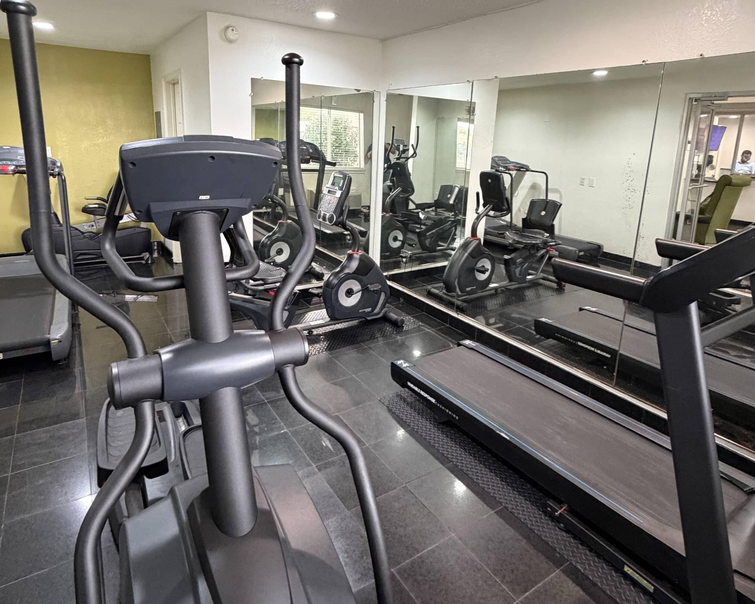 A gym with exercise equipment including treadmills and elliptical machines.