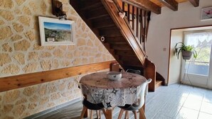 Ein Essbereich mit einem runden Tisch, Holzbalken, Steinwänden und einer Treppe.