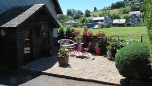 Eine Holzhütte mit einer Terrasse, die Sitzgelegenheiten und Kübelpflanzen bietet.