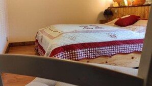 Ein Schlafzimmer mit einem Bett, einer Holzzahlende und einer kleinen Wandleuchte.