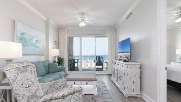 A living room with a sofa, armchair, TV, and a balcony with a view. - Gulf Front 3rd Floor 2/2 - Large Balcony - Keyless Entry - Steps From the Beach (Gulf Shores)