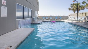 A swimming pool with lounge chairs, a lifeguard sign, and a palm tree. - Gulf Front 3rd Floor 2/2 - Large Balcony - Keyless Entry - Steps From the Beach (Gulf Shores)