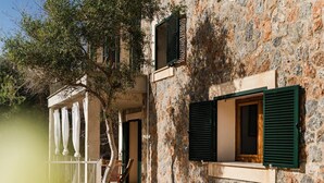 Ein Gebäude aus Stein mit Balkon, Treppe und einem Fenster mit Rollläden.