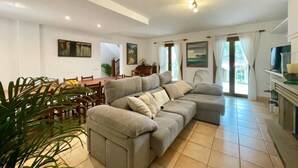 Ein Wohnzimmer mit einer Couch, einem Esstisch, Stühlen und einem Fernseher.