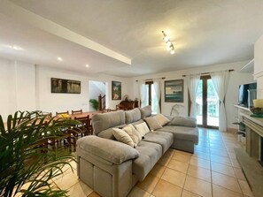 Ein Wohnzimmer mit einer Couch, einem Esstisch, Stühlen und einem Fernseher.