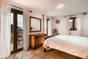 Ein Schlafzimmer mit Bett, Schminktisch, Spiegel und Balkontür.