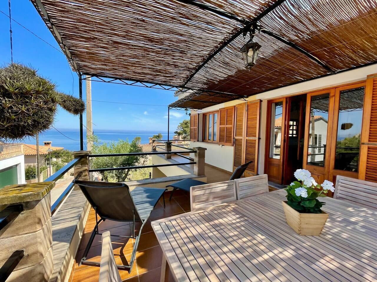 A terrace with a table, chairs, and a potted plant.