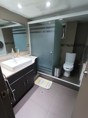 A bathroom with a white sink, dark cabinets, a glass shower enclosure, and a toilet. - Complete apartment in Polanco | 8 Bedrooms, 4 Bathrooms (Ciudad de México)
