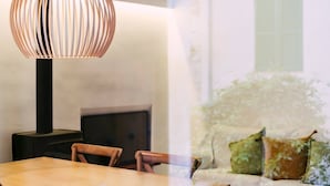En modern inredning med ett bord, stolar, en lampa och en soffa med kuddar.