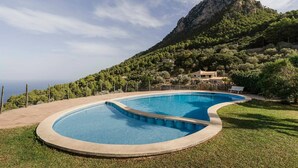 A swimming pool with a curved design, surrounded by a grassy area and a fence. - House "Tramuntana" - Valldemossa (Son Maxella)