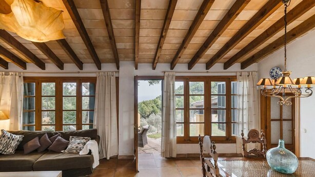 A cozy living room with a sofa, a dining table with chairs, and large windows with shutters. - House "Tramuntana" - Valldemossa (Son Maxella)