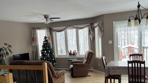 Ein geräumiges Wohnzimmer mit Essbereich, Deckenventilator und Weihnachtsbaum.