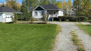 Ein zweistöckiges Haus mit Veranda, Kiesauffahrt und gepflegtem Rasen.