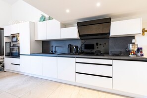 A modern kitchen with white cabinets, a black countertop, and a built-in oven. - Aria Marina 37 - climatisé et vue mer (Lumio)