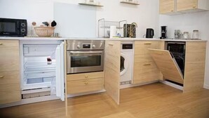 Ett kompakt kök med inbyggda vitvaror, träinredning och en mikrovågsugn.