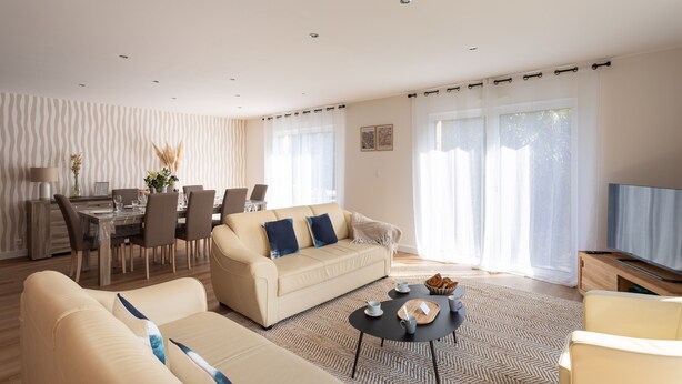 Una sala de estar moderna con un sofá, una mesa de comedor y una televisión.