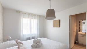 Habitación de hotel con cama, lámpara de noche, baño con espejo y perchero para toallas.