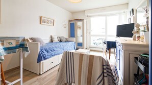 Ein Schlafzimmer mit Bett, Schreibtisch, Stuhl, Kleiderschrank und Fenster.