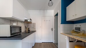 Eine kleine Küche mit weißen Schränken, einer Mikrowelle und einer Holz Arbeitsplatte.